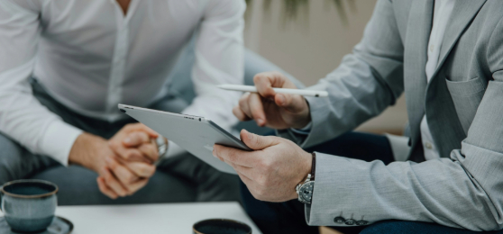 zwei Maenner sitzen mit einem Tablet an einem Tisch Thumbnail